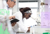 A scientist inspects a specimen through a microscope.