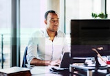 A young professional sits at a computer terminal.