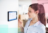 A woman checking the smart thermostat in her home.